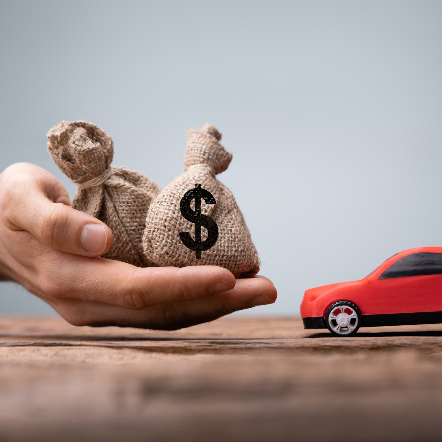 Mão com sacos de dinheiro ao lado de um carro – crédito com garantia